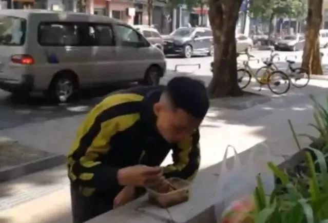 外卖小哥站路边吃饭被店主请进屋